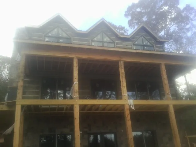 Dormers and porch framing on a large log home under construction — Roof Coating work by our crew in La Harpe