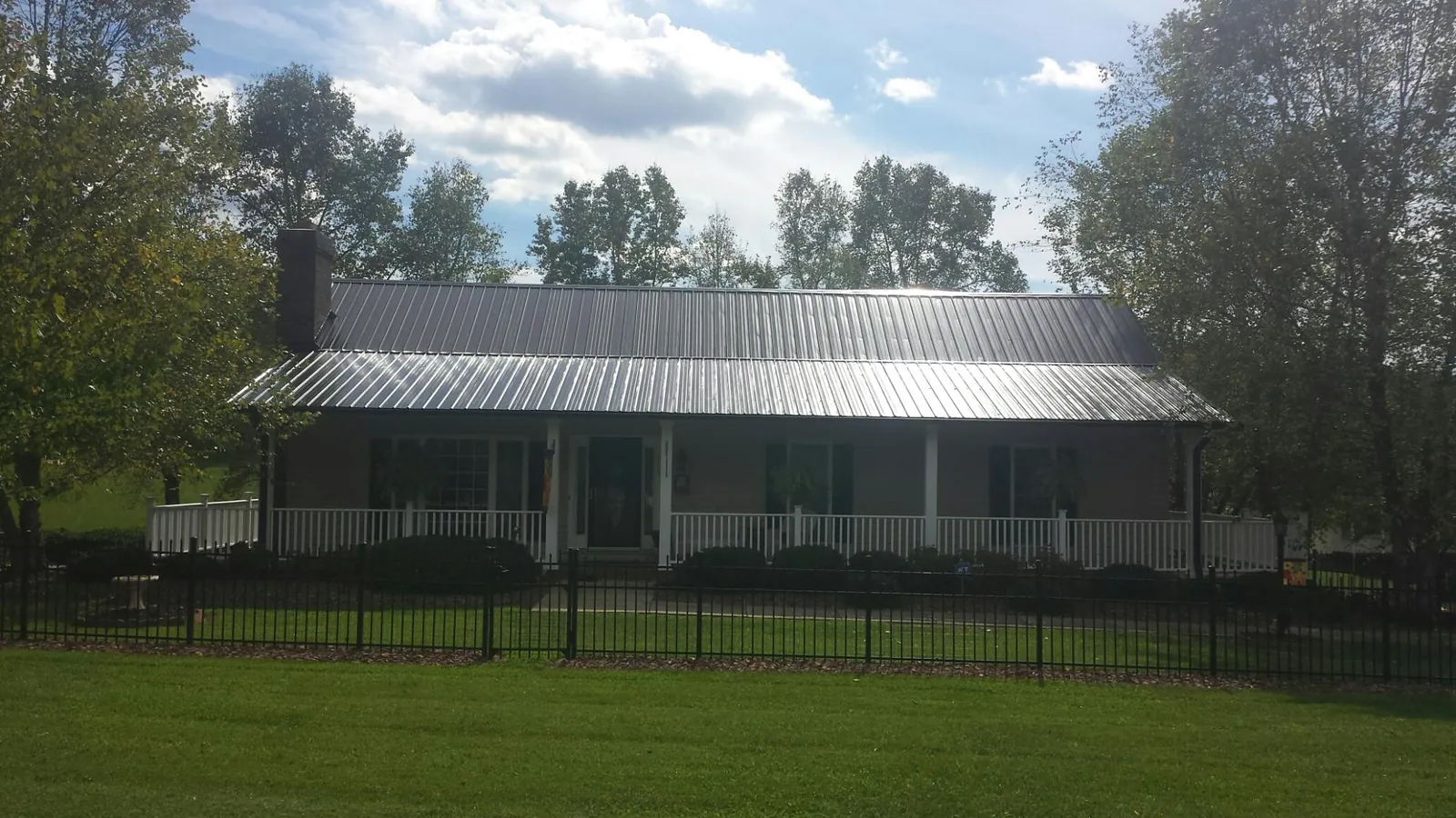 Gray metal roof on a brick ranch with a full width front porch — Gutter Guard Installation work by our crew in La Harpe