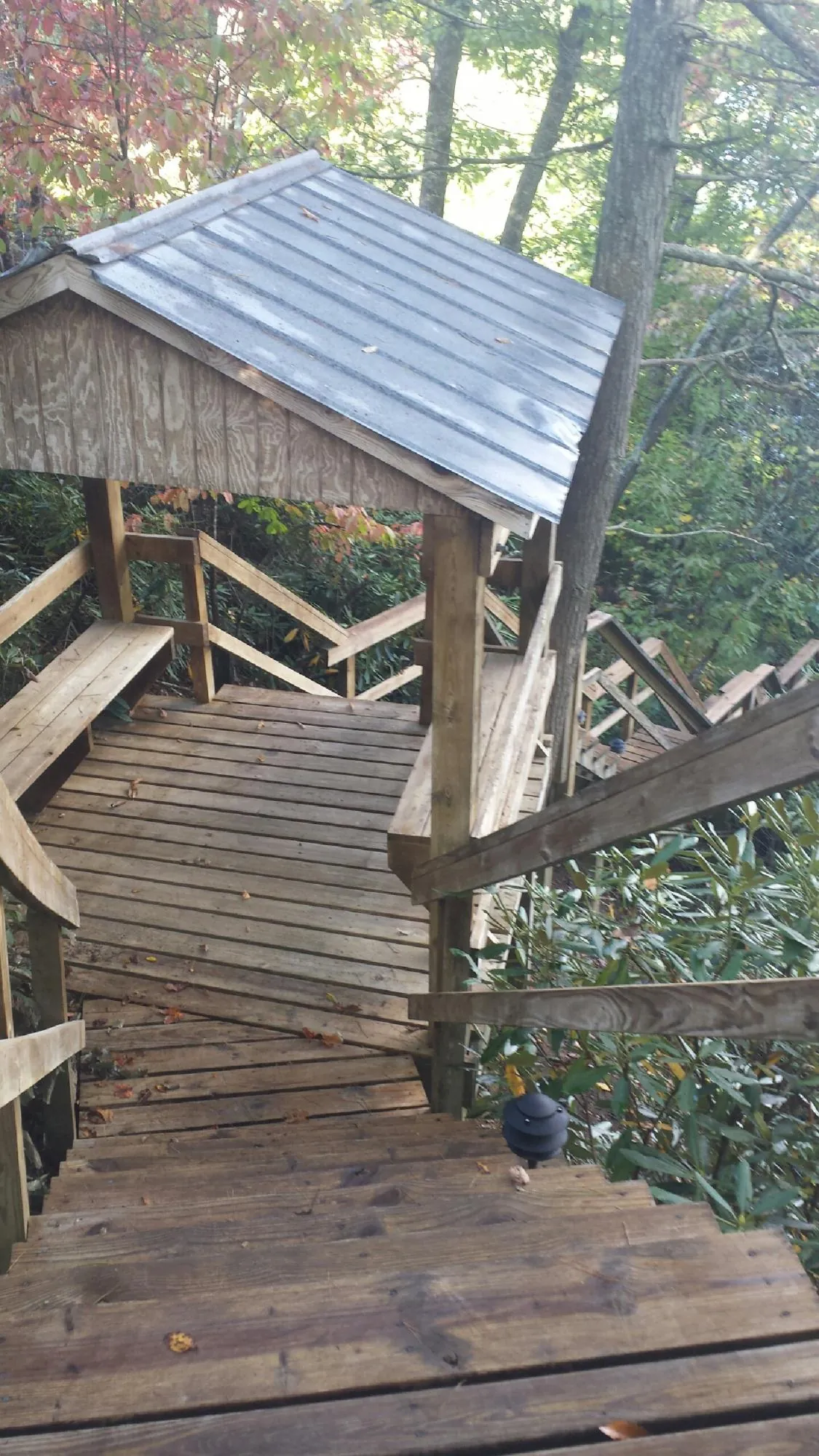 Metal roofed shelter over wooden steps on a wooded walkway — Skylight Repair & Installation work by our crew in La Harpe