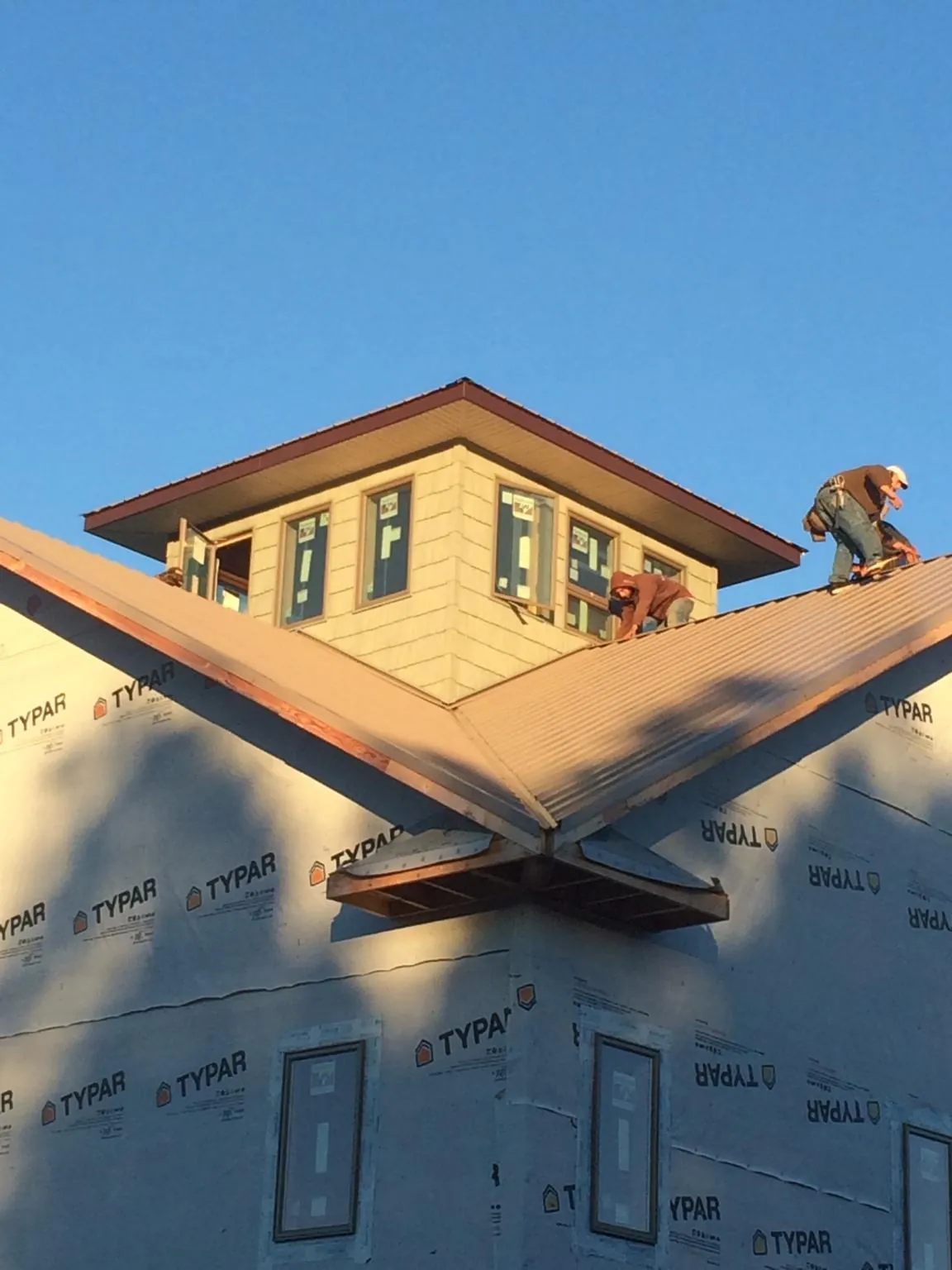 Roofers working around a rooftop cupola on a new metal roof at sunset — Roof Waterproofing in La Harpe by Roofing Brothers